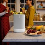 Sonos speaker on a kitchen counter playing music during a holiday gathering with friends.